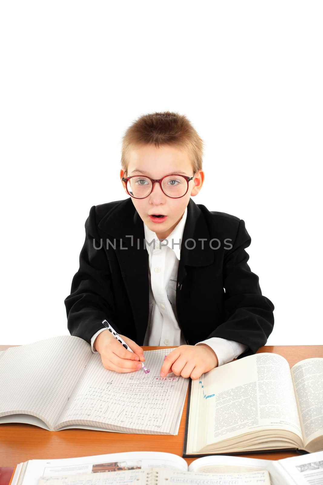 amazed schoolboy in glasses sitting in the classroom