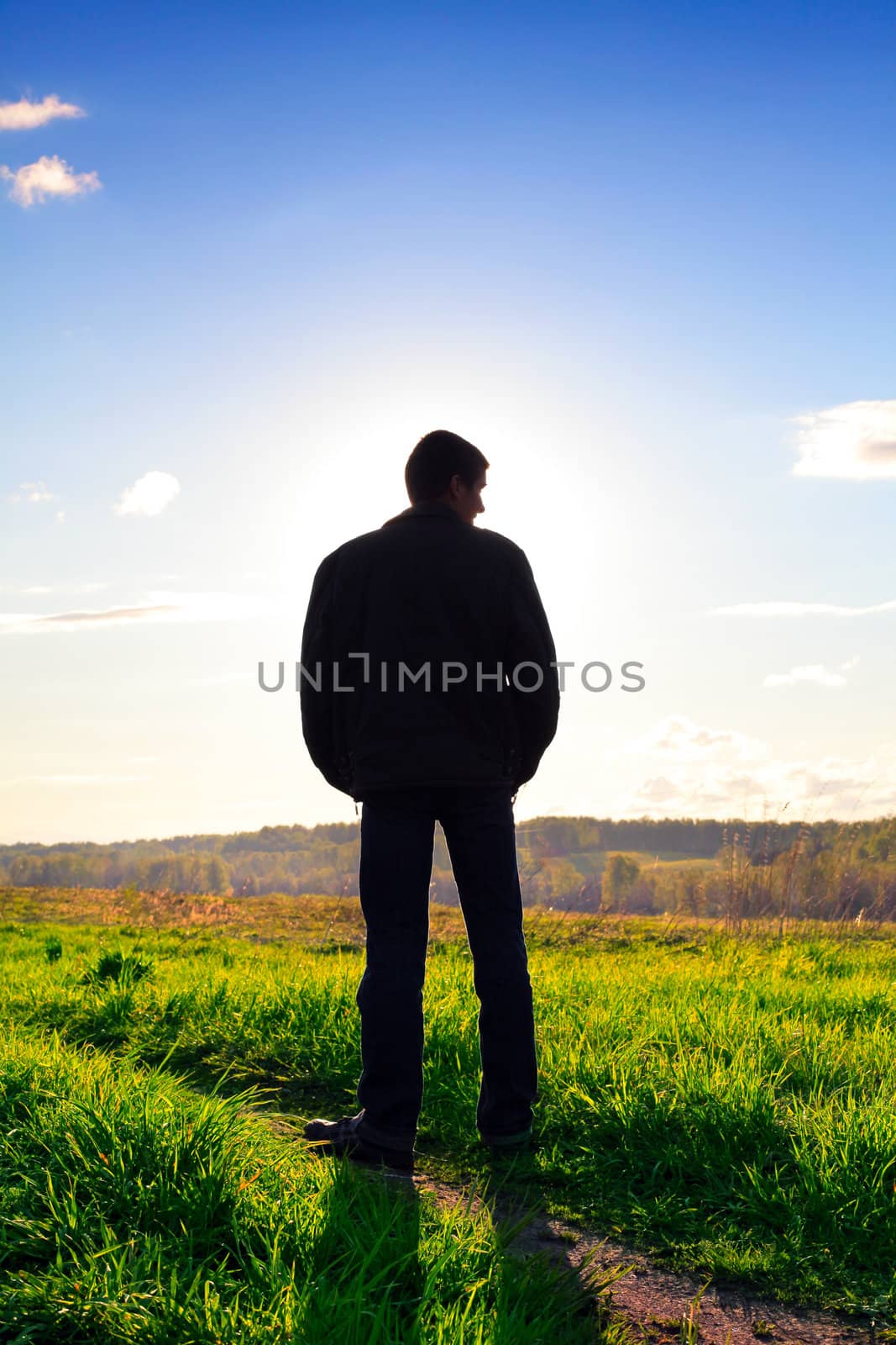 man silhouette in the summer field against the sunlight