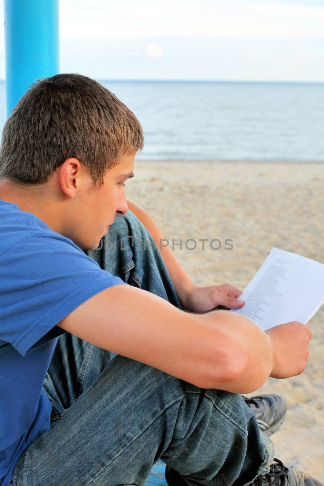 teenager looking on sheet of paper on the empty beach