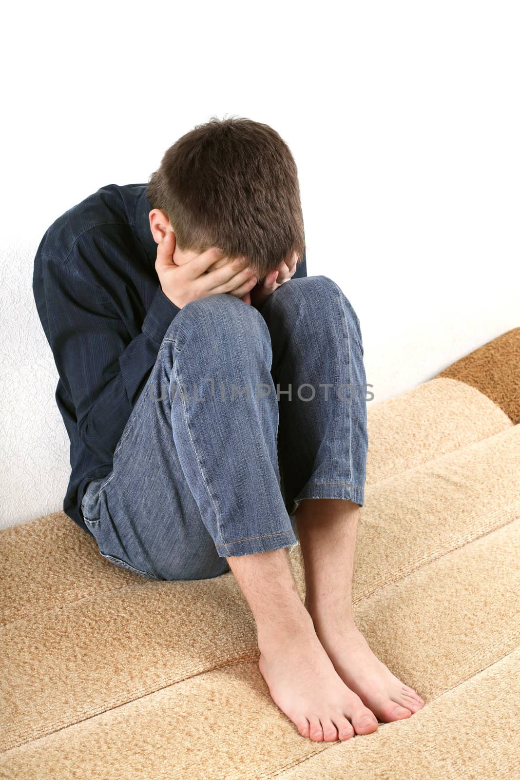 sad teenager sitting on the bed in home interior