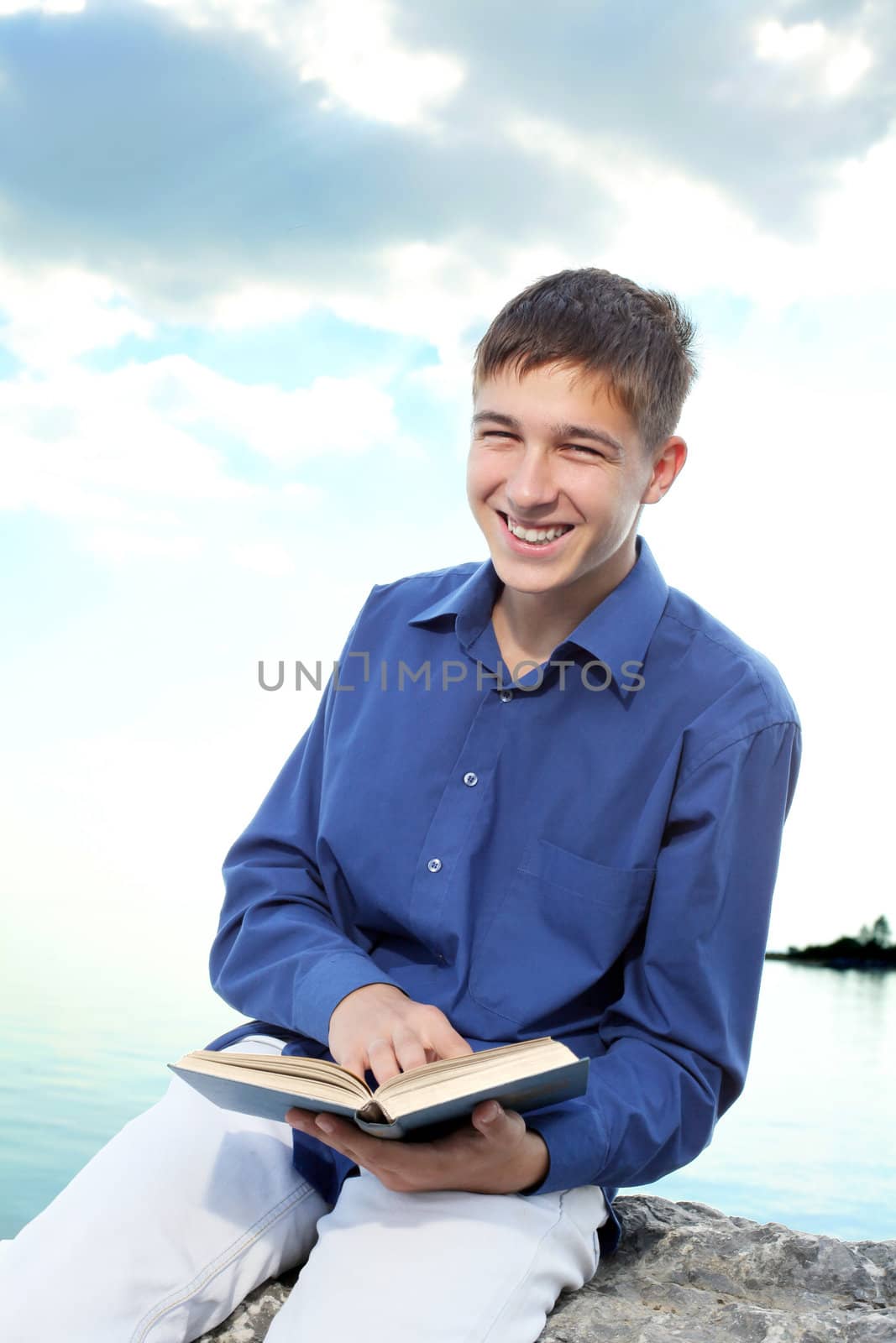 happy teenager sitting with a book on the stone