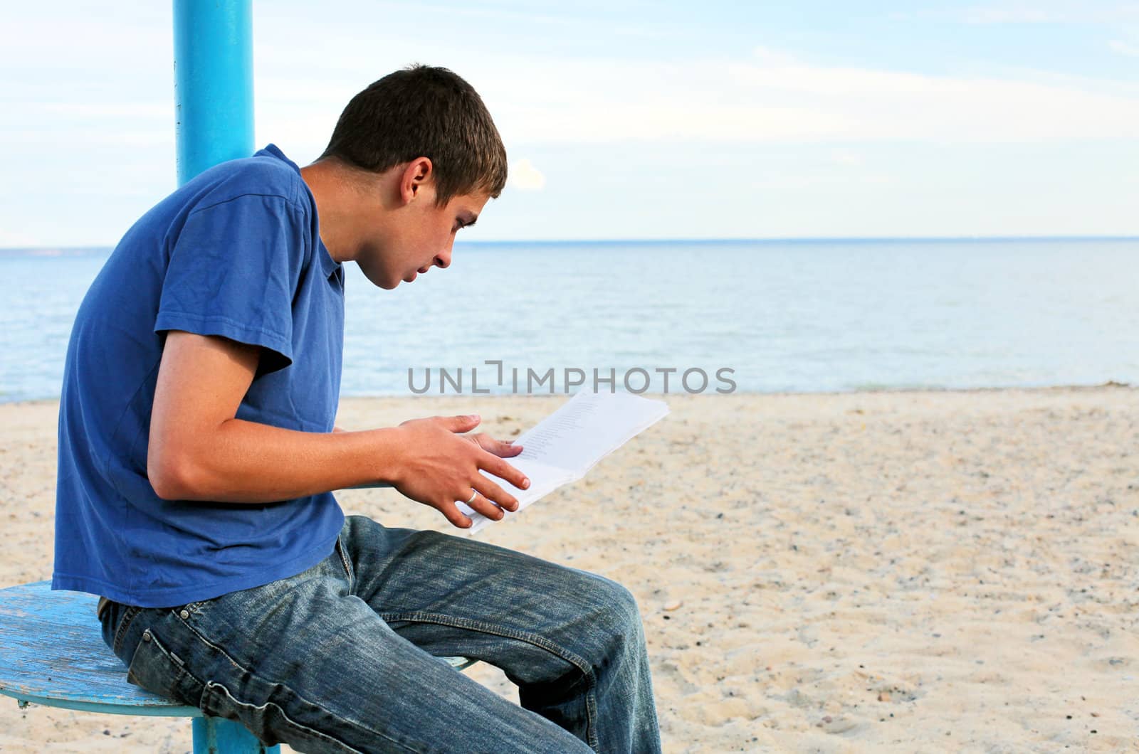 teenager looking on sheet of paper on the empty beach