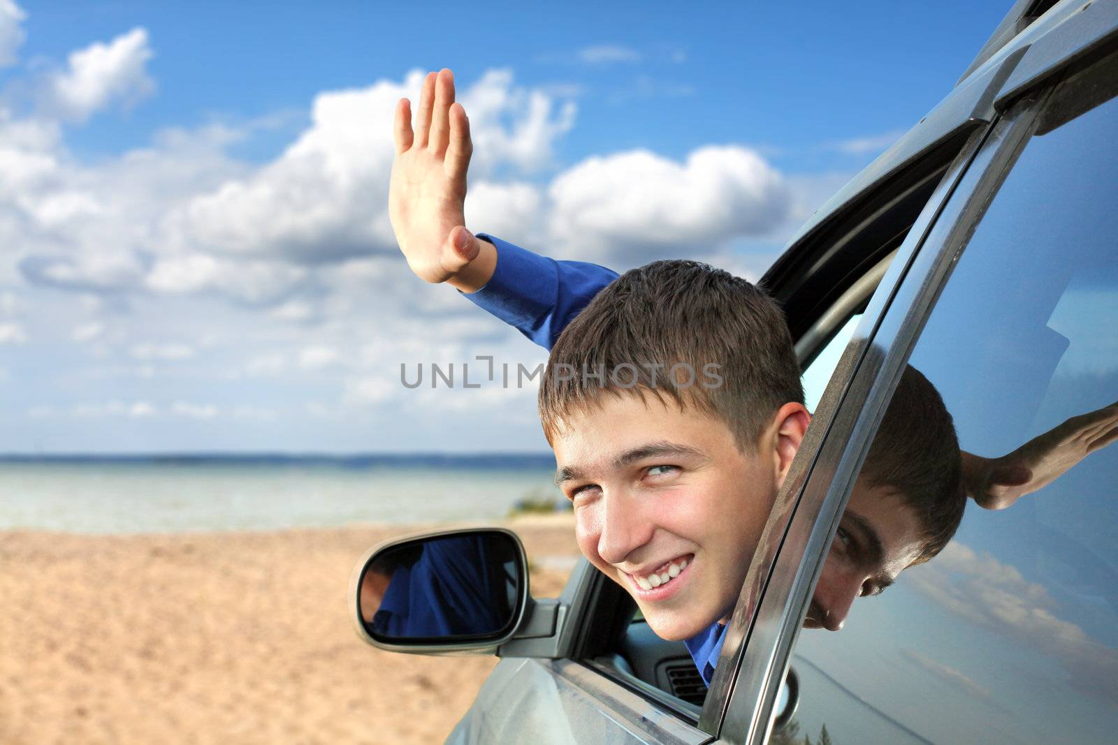 happy young man sitting in the car and wave goodbye