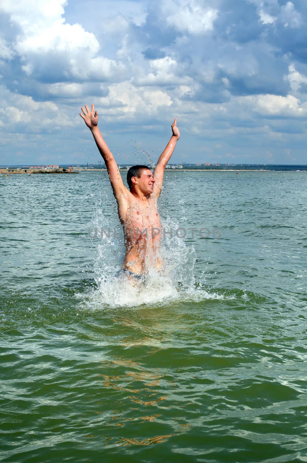 happy young man jumping and bathing in the sea