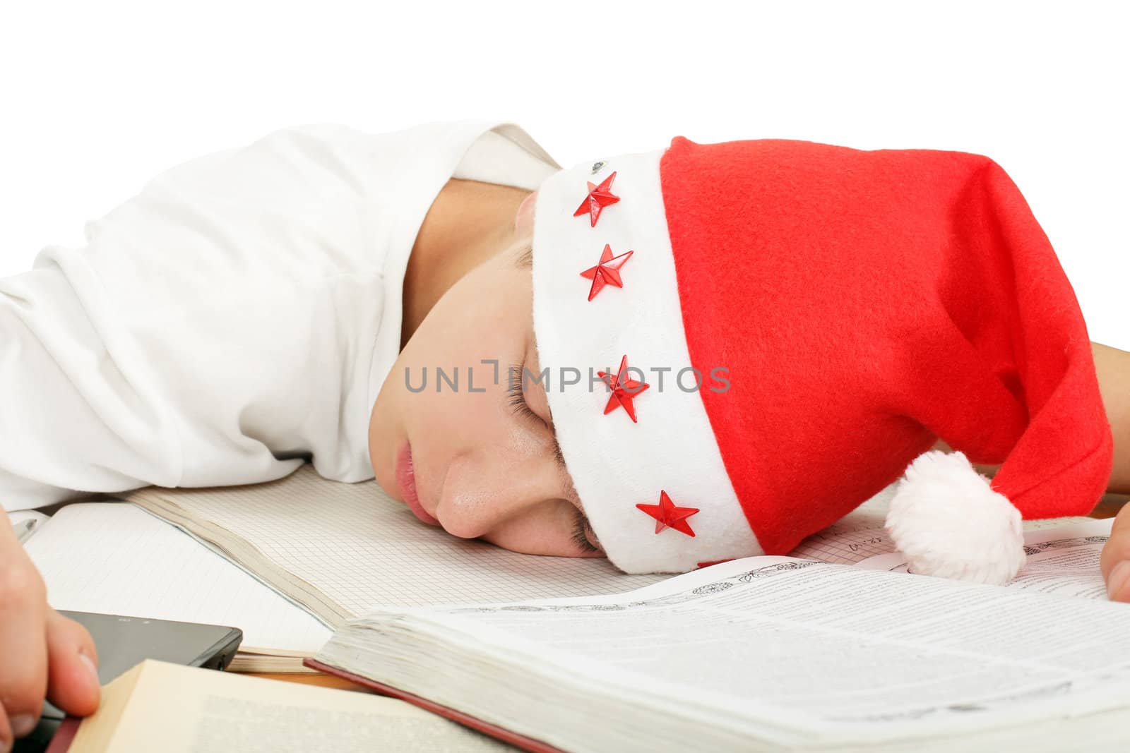 tired student in santa's hat sleeping on school desk after hard work for exam