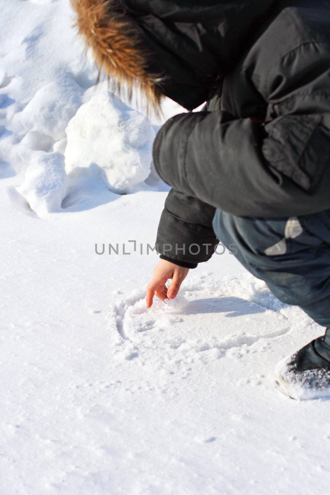 Boy Draws on the Snow in Winter