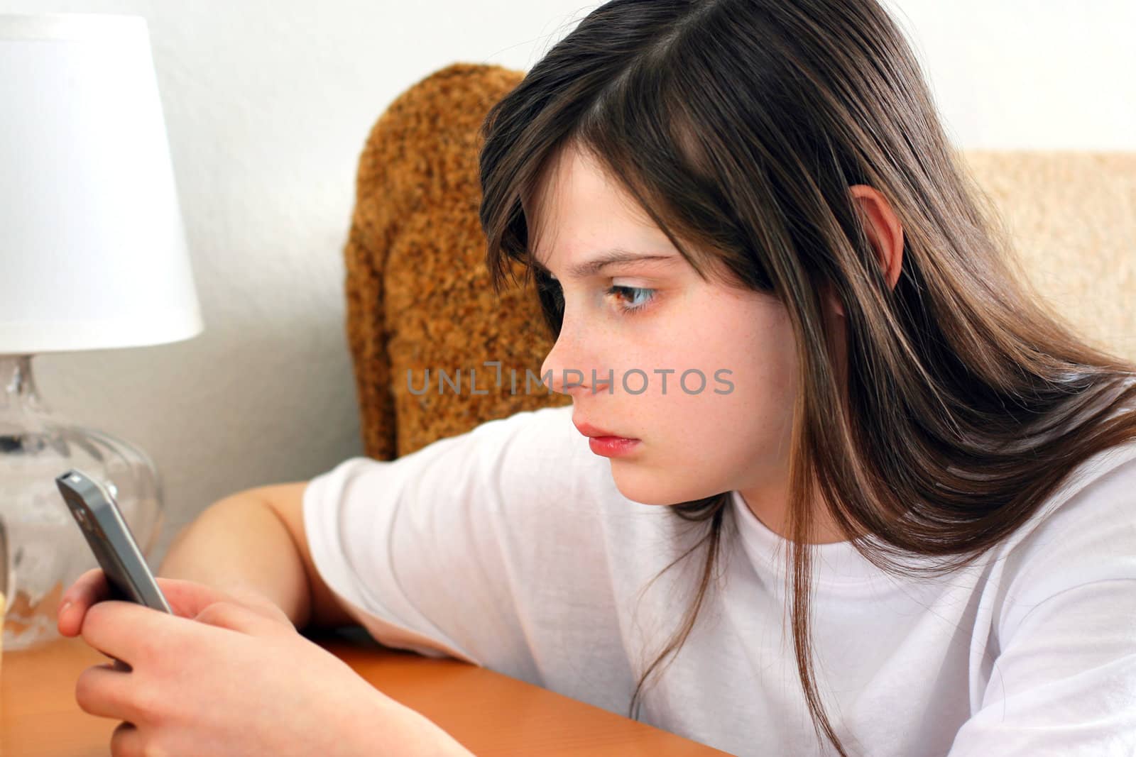 Sad Teenage Girl with Mobile phone at the Home