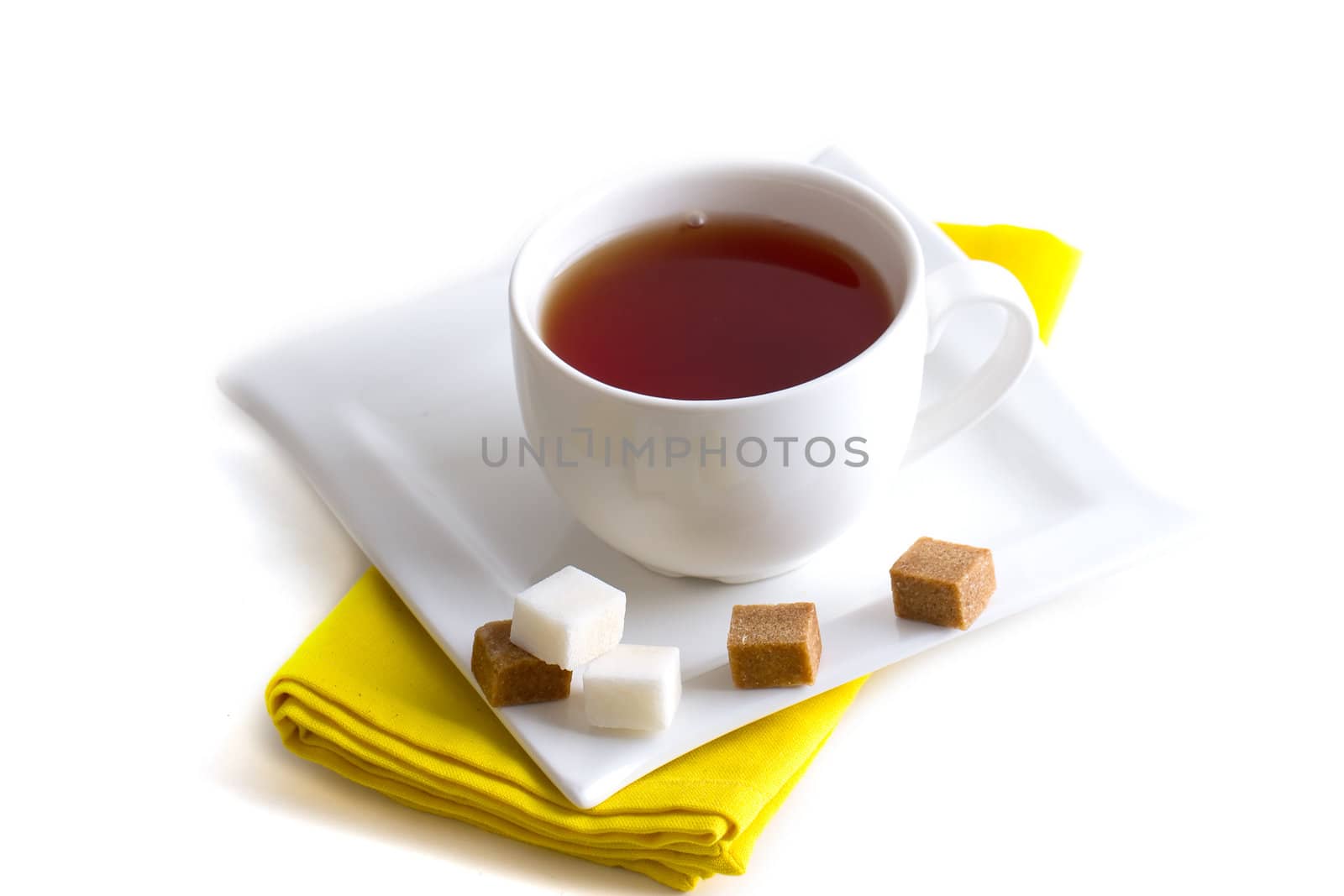 White cup of tea on a napkin with pieces of sugar