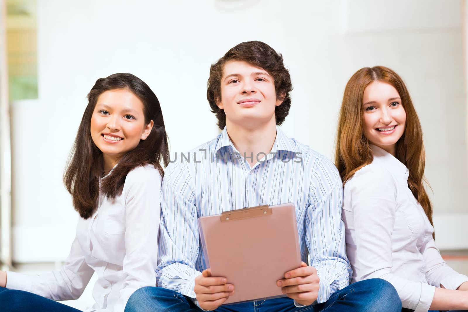 portrait of a group of young people sitting on the floor, man and two attractive women