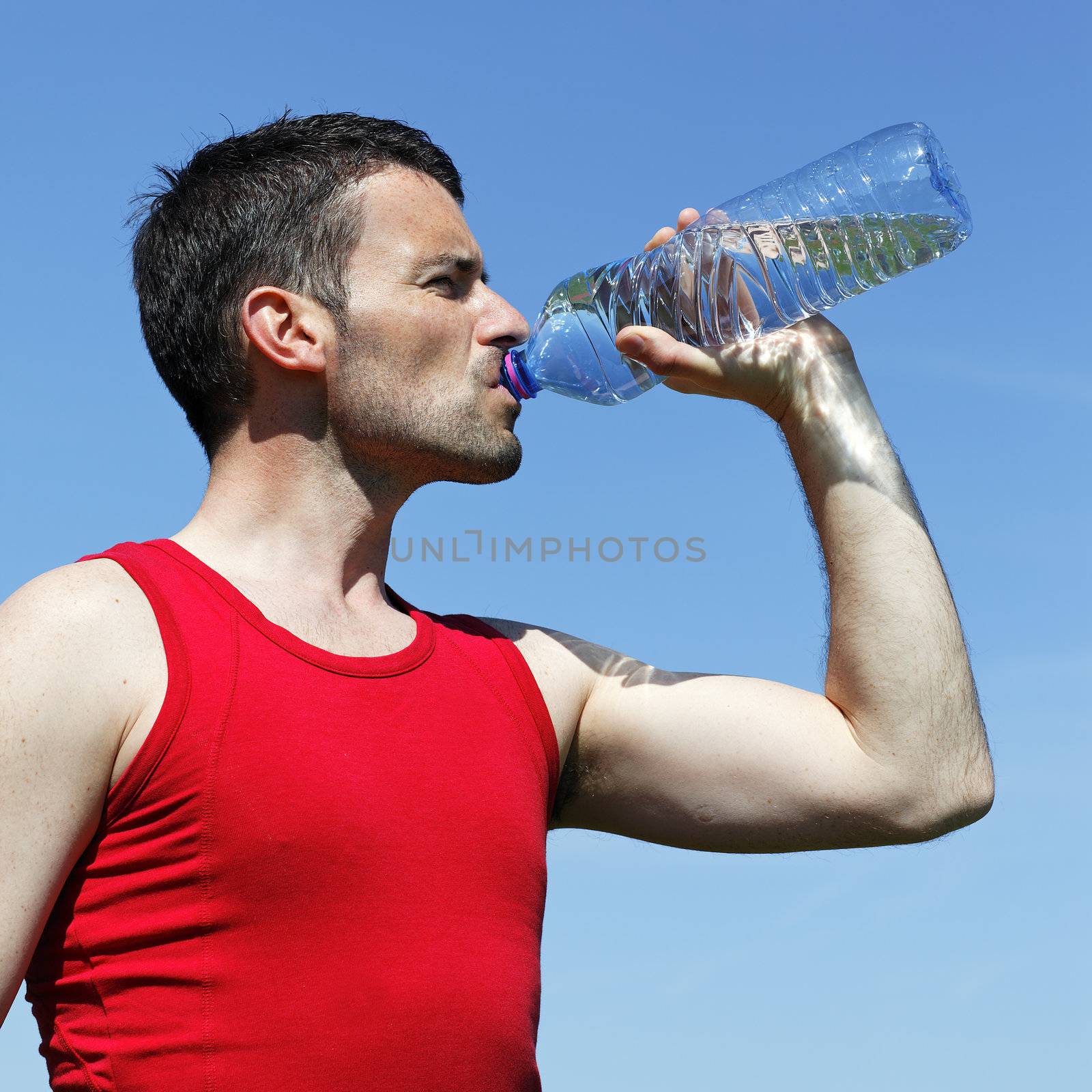 man drinking water after sport in blue sky