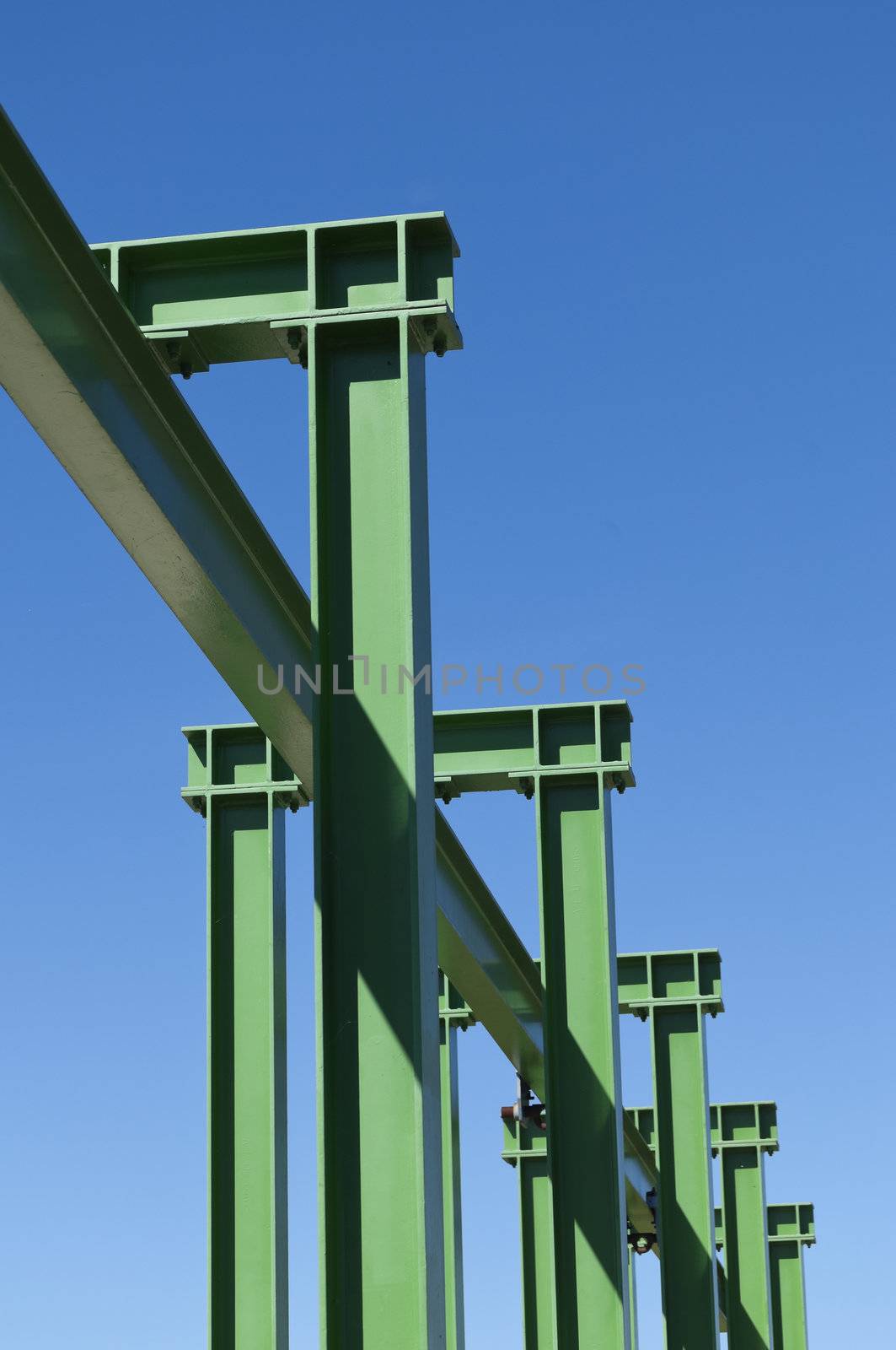 Detail of a small gantry crane painted green against the blue sky