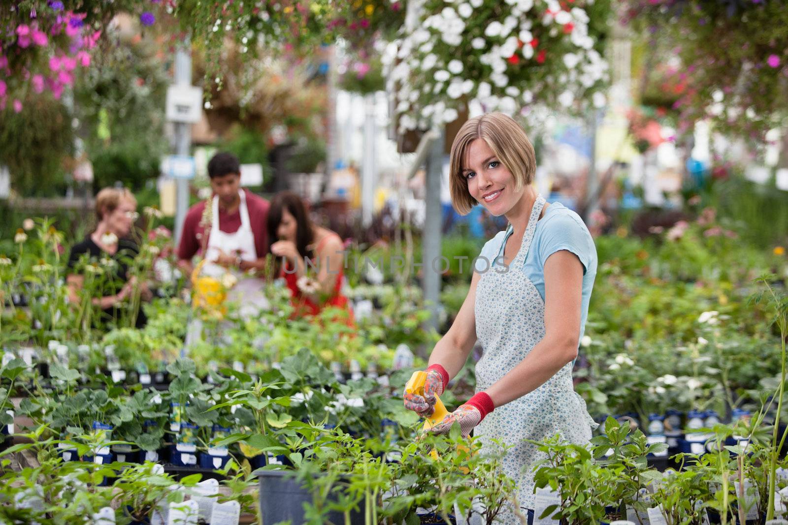 Beautiful woman spraying water on plants by leaf