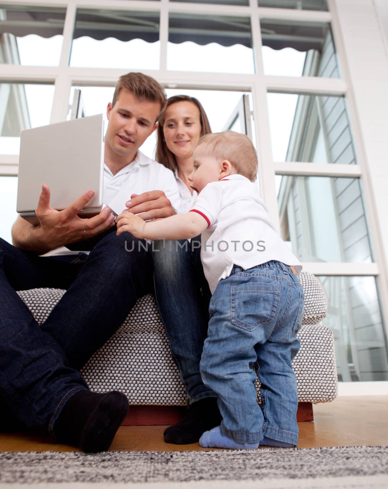 Young toddler son trying to view laptop coputer with parents