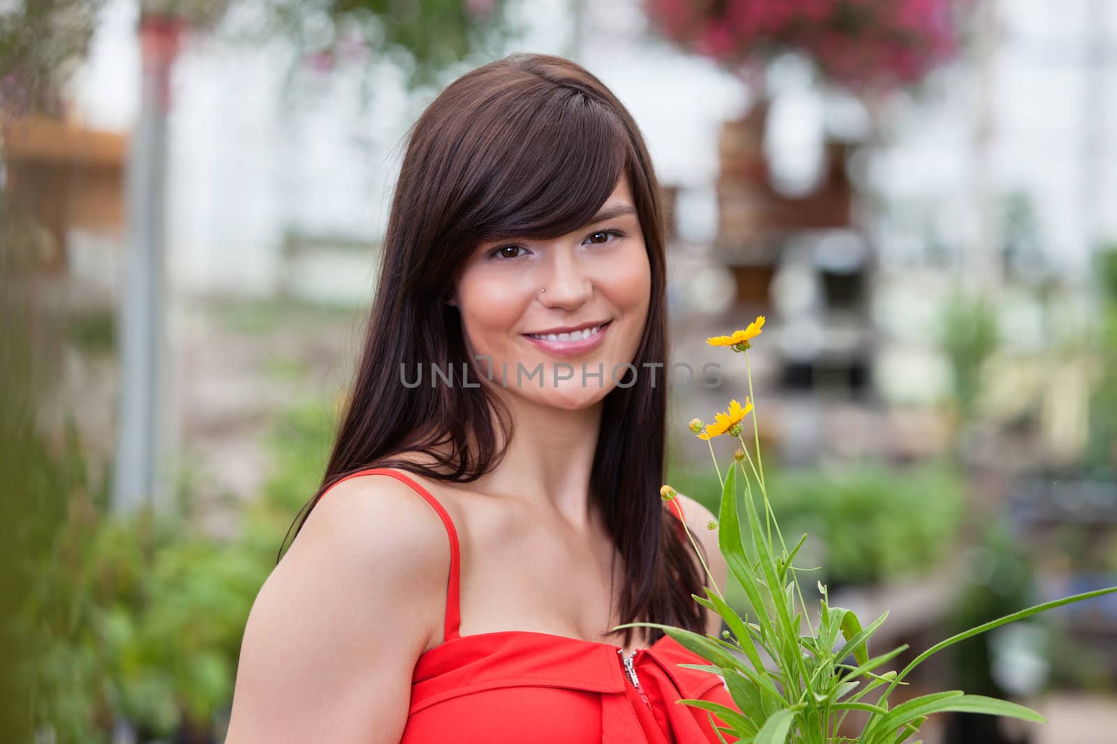 Smiling woman holding flower pot by leaf