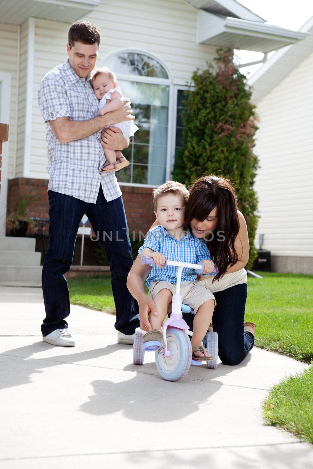 Mother Teaching Son To Ride Tricycle by leaf