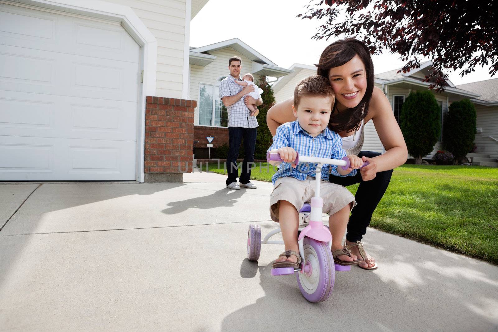 Loving Mother Teaching Son To Ride Tricycle by leaf