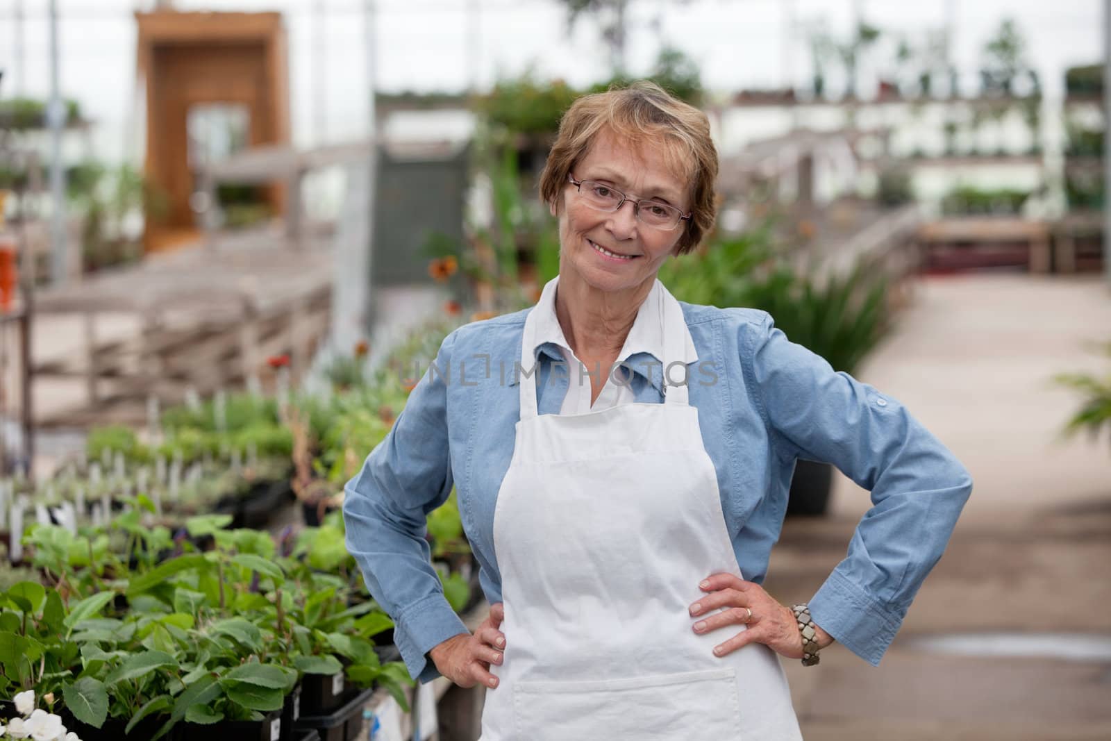 Smiling senior female worker by leaf