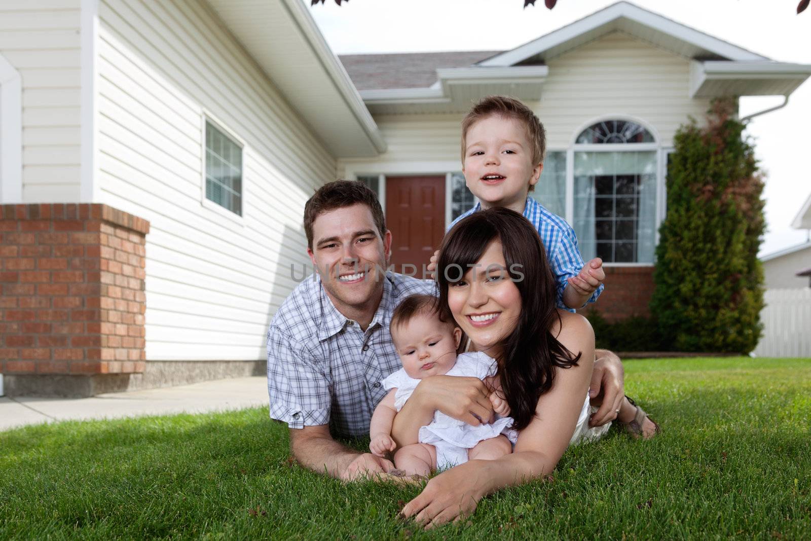 Happy Family of Four Lying Down on Grass by leaf