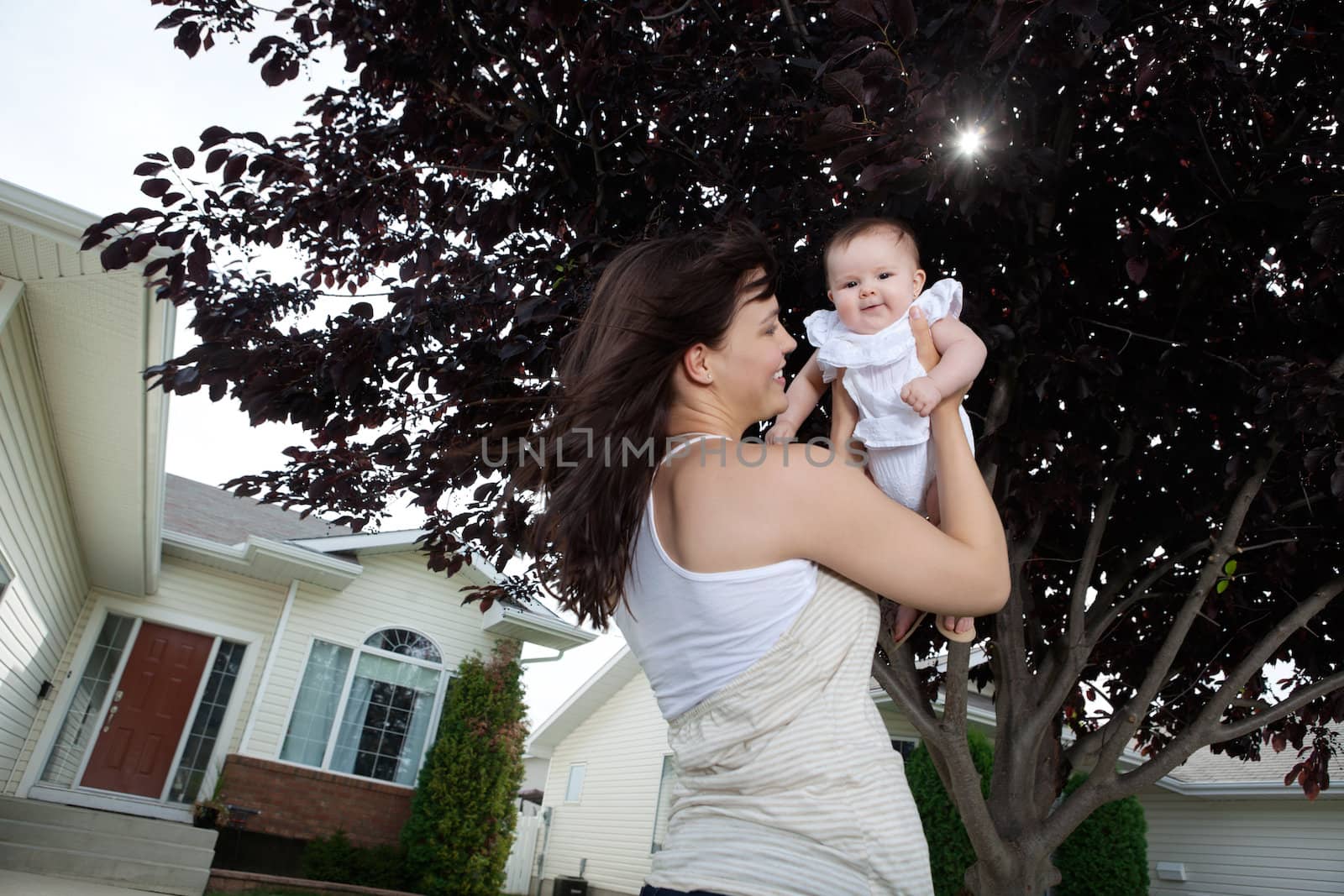 Happy mother holding up her adorable daughter