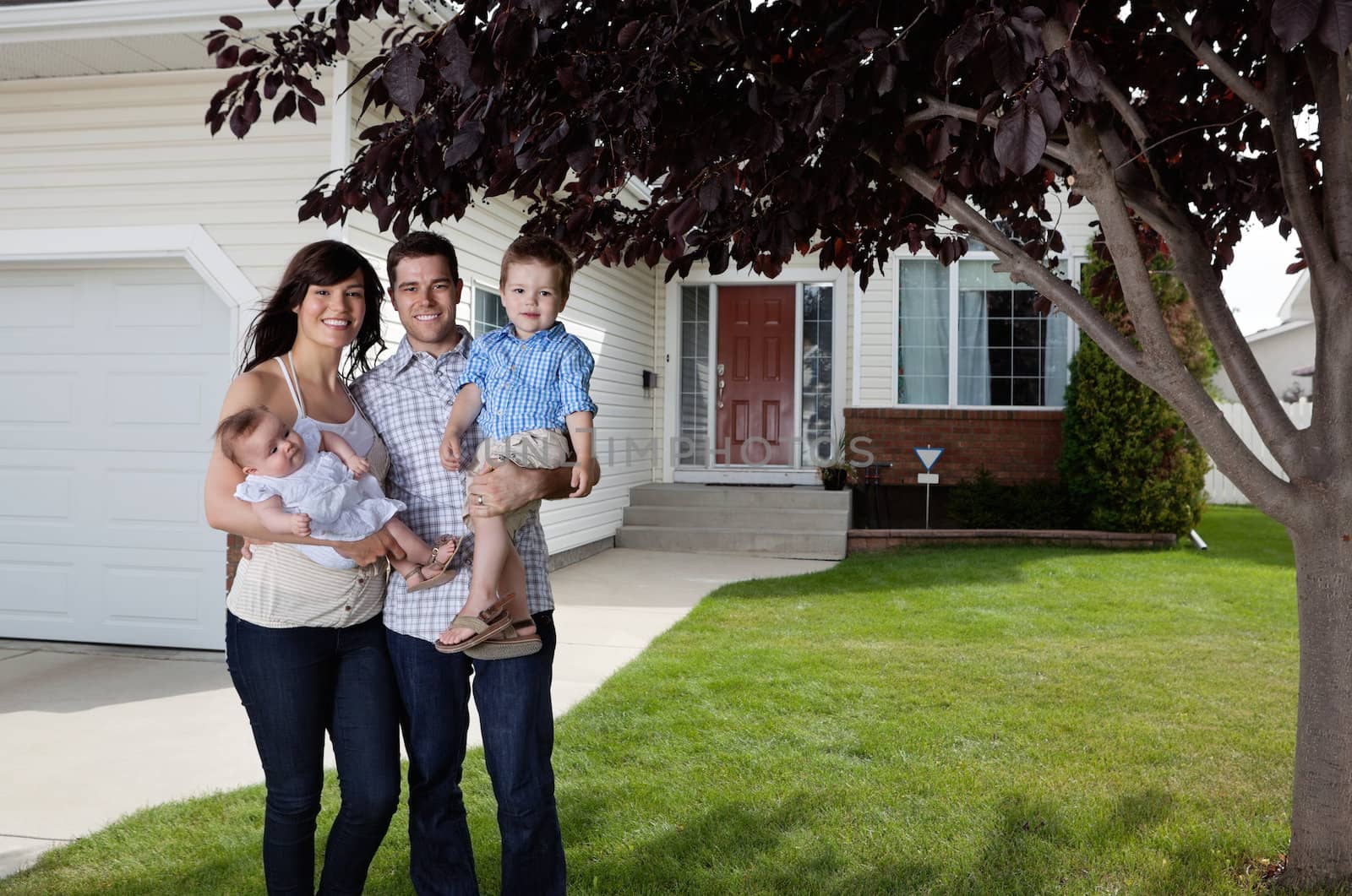 Happy Couple Standing With Their Children by leaf