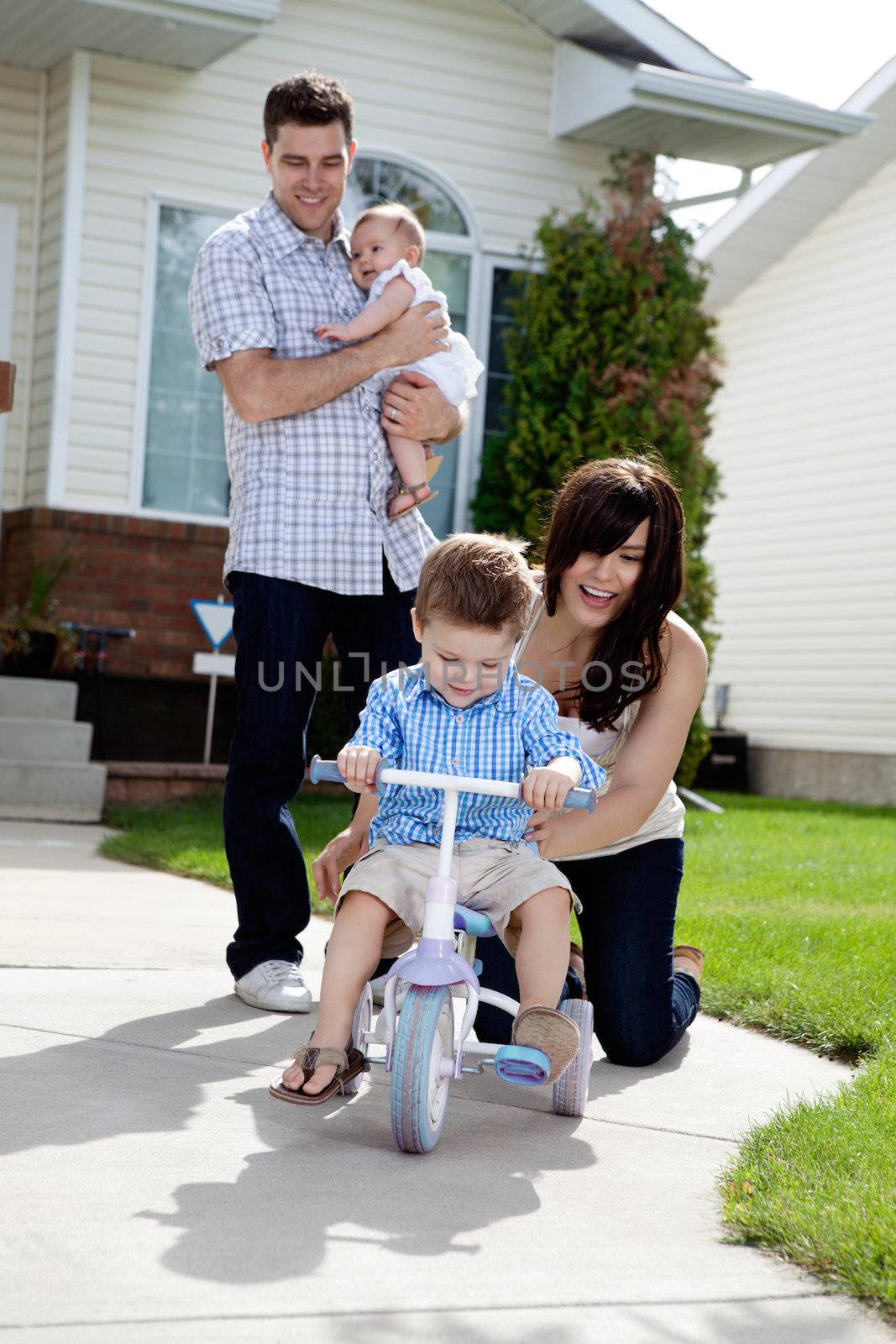 Cheerful Mother Teaching Son To Ride Tricycle by leaf