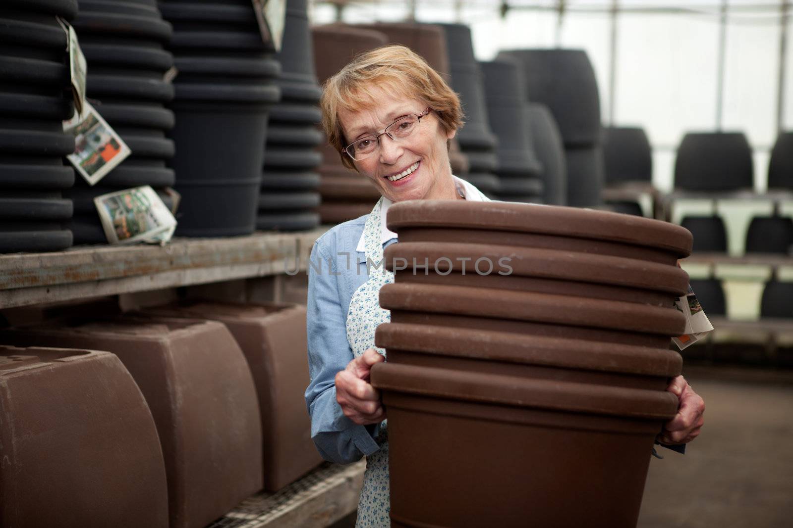 Portrait of a senior worker in garden center with large plant pots