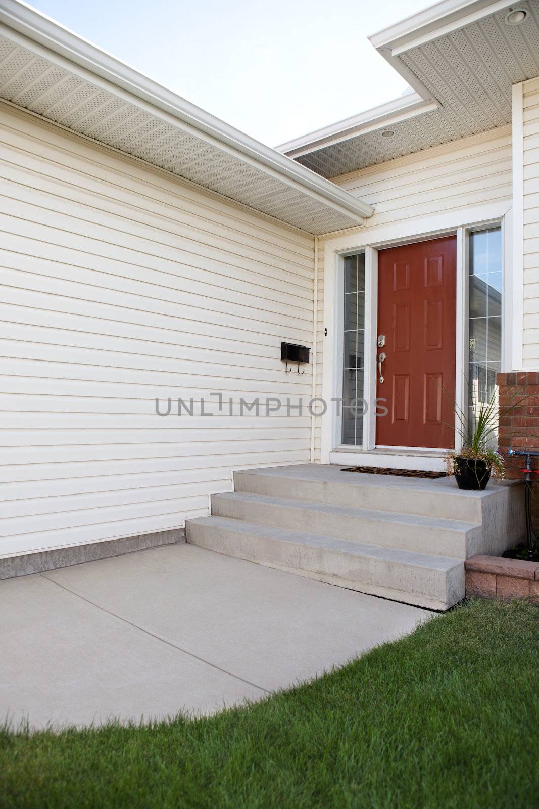 Exterior of residential house with closed door and potted plant on the porch