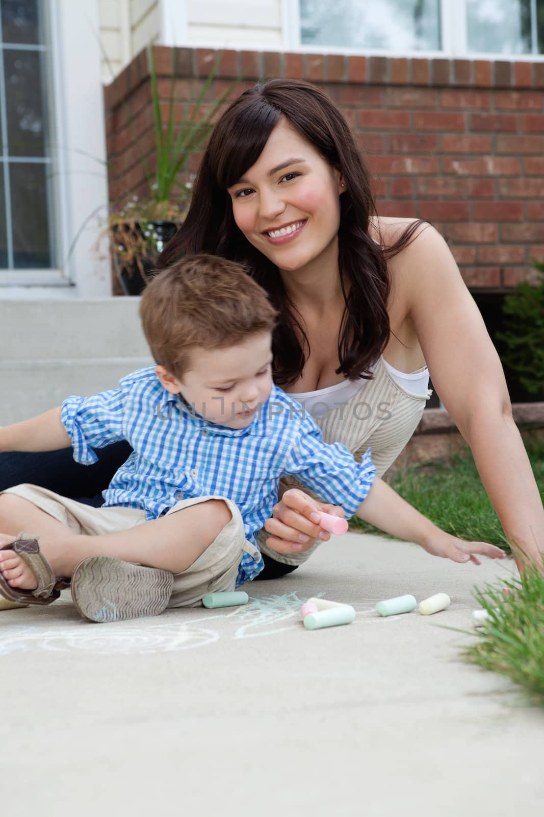Mother and Son Playing with Sidewalk Chalk by leaf