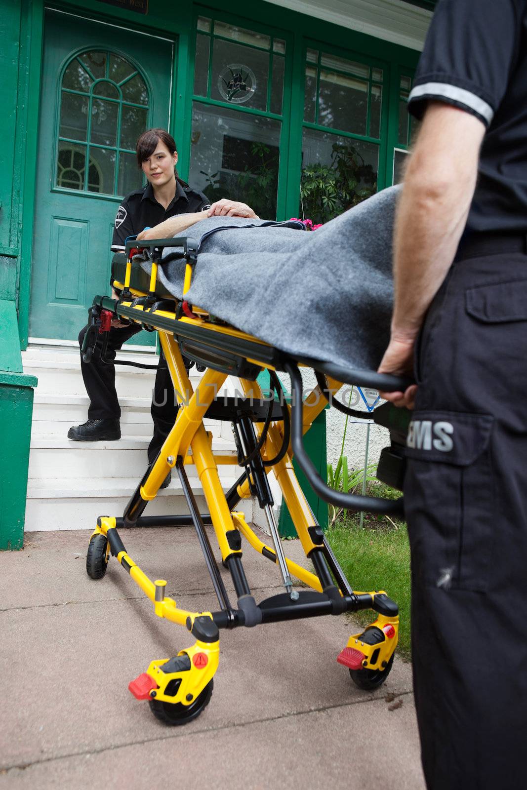 Ambulance workers with a stretcher outside a house