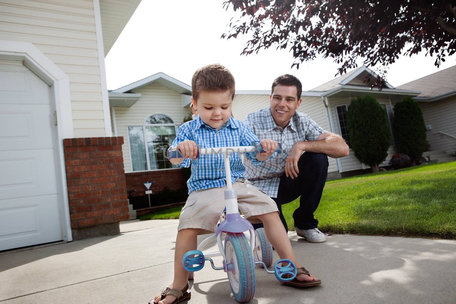 Father teaching Son To Ride a Tricycle by leaf