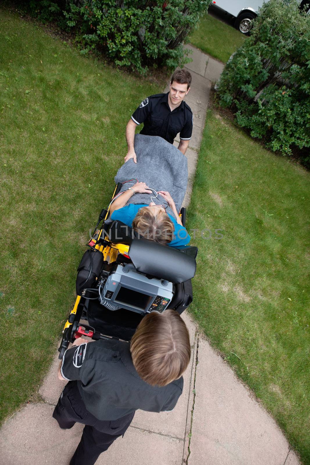 Overhead view of emergency medical team pushing senior woman on stretcher.  Shallow DOF sharp focus on patient