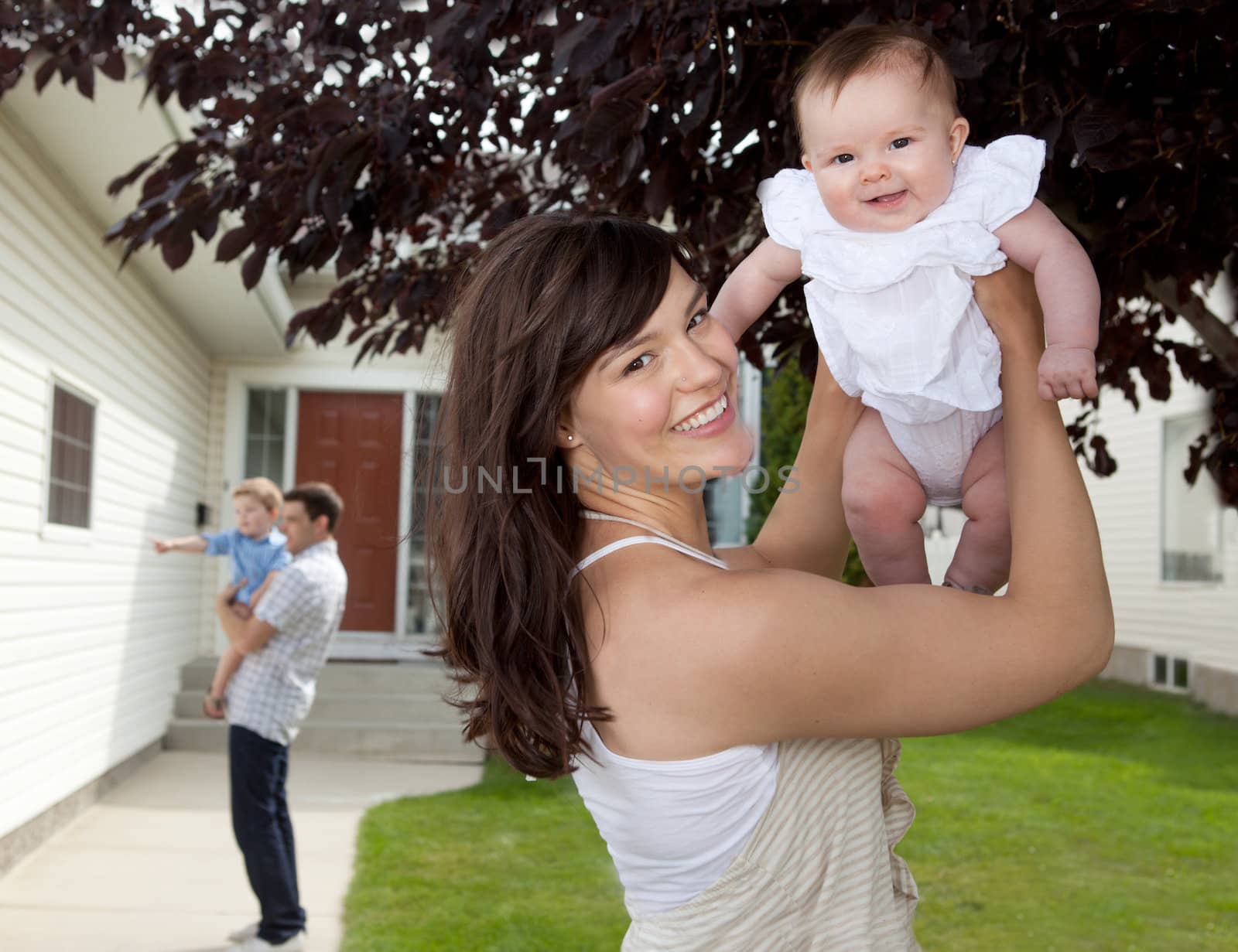 Portrait of mother and daughter in front of house with father and son in background