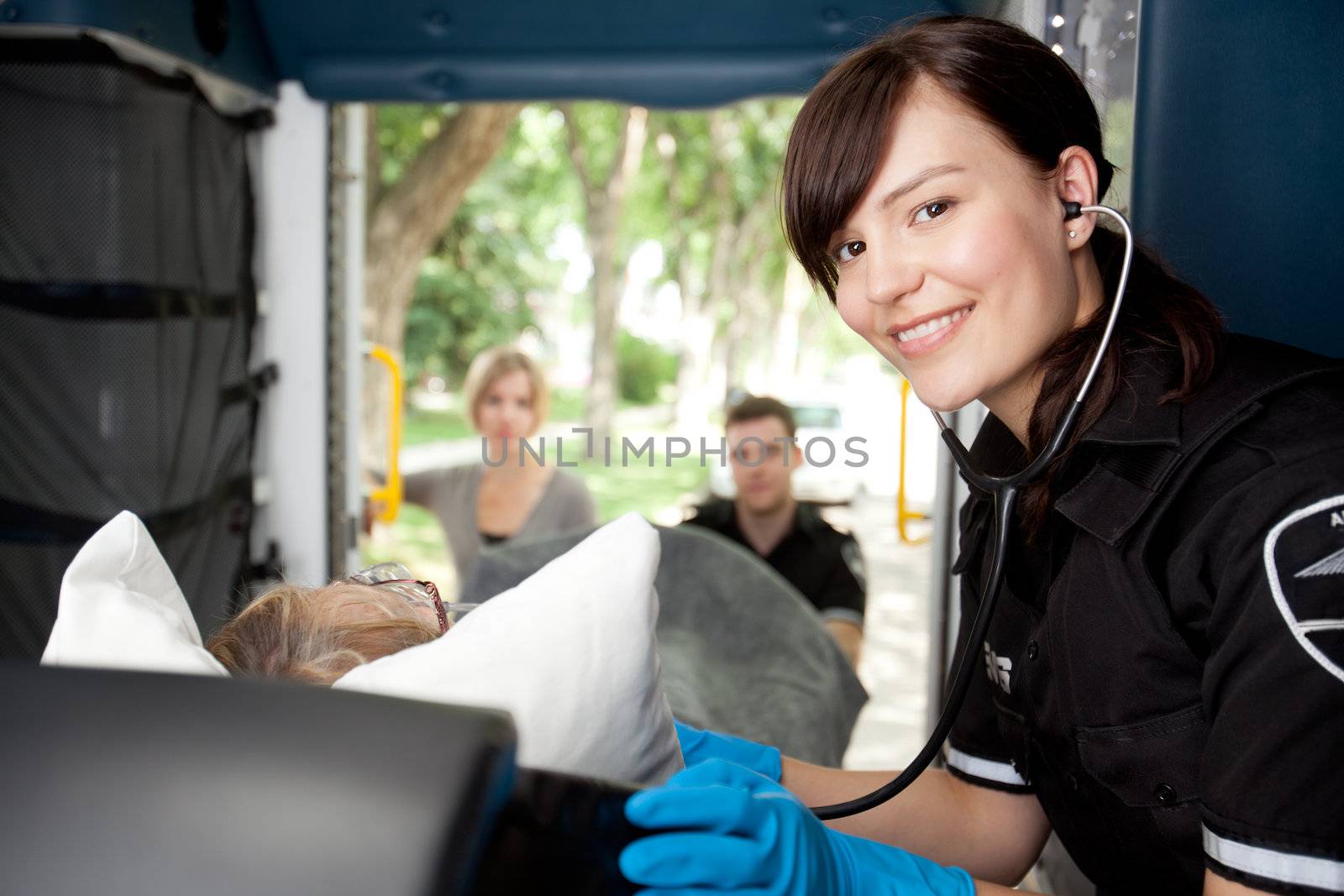 Portrait of a paramedic listening to heart rate of patient in ambulance