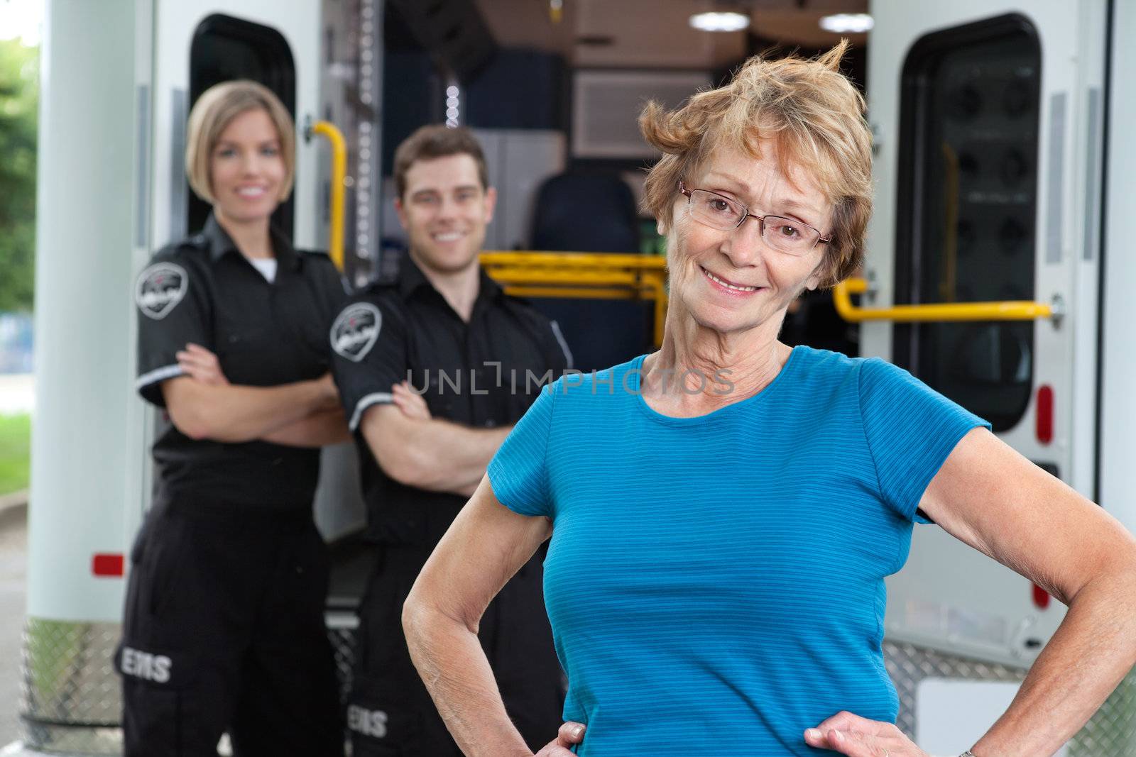 Portrait of elderly patient with ambulance workers in background