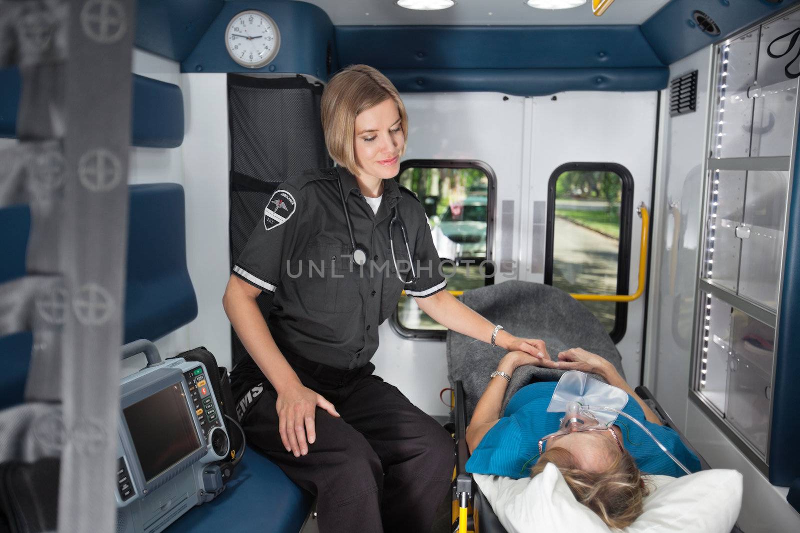 Female EMT worker showing care to senior woman patient inside ambulance
