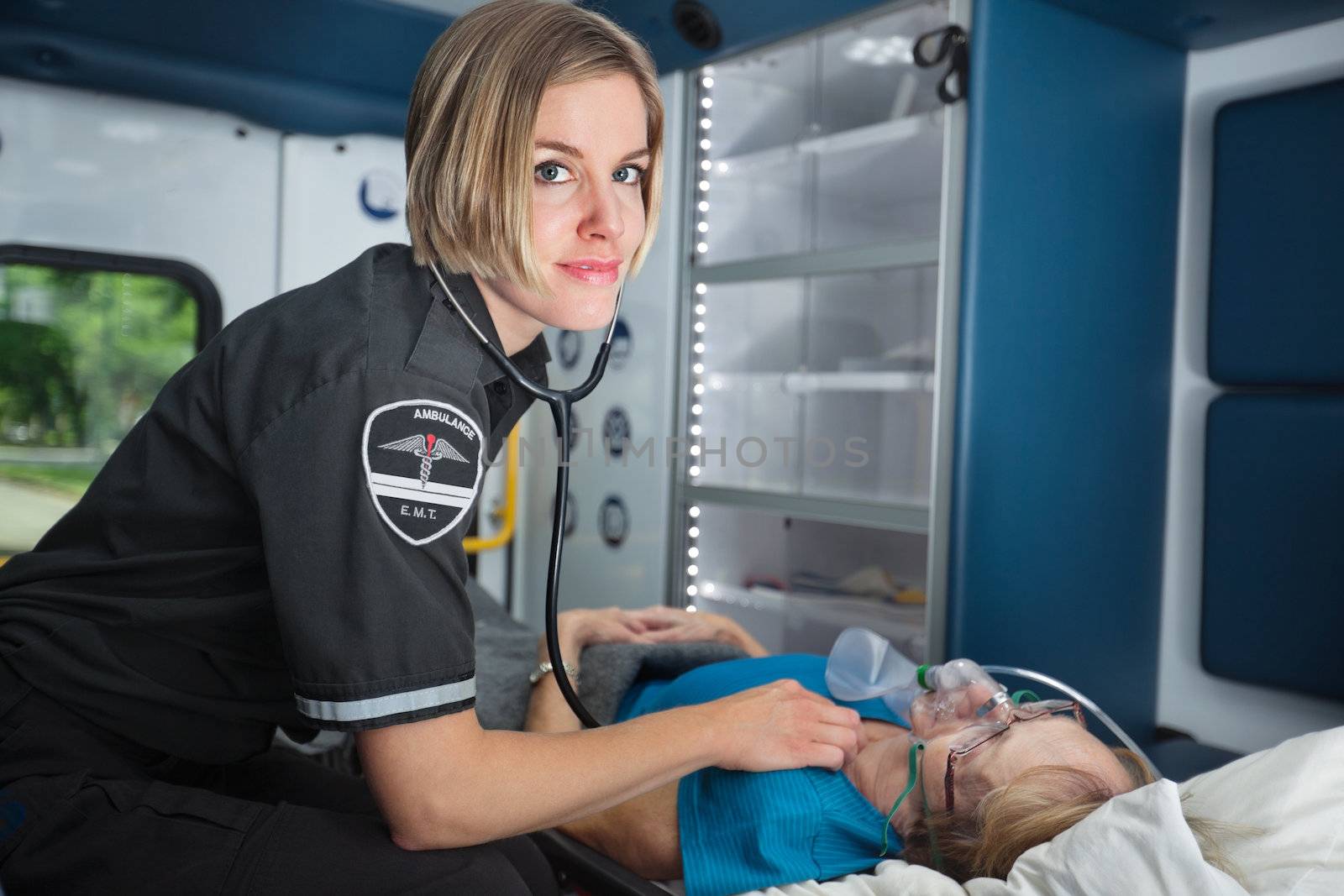 Portrait of a happy EMT worker inside ambulance tending to senior woman patient