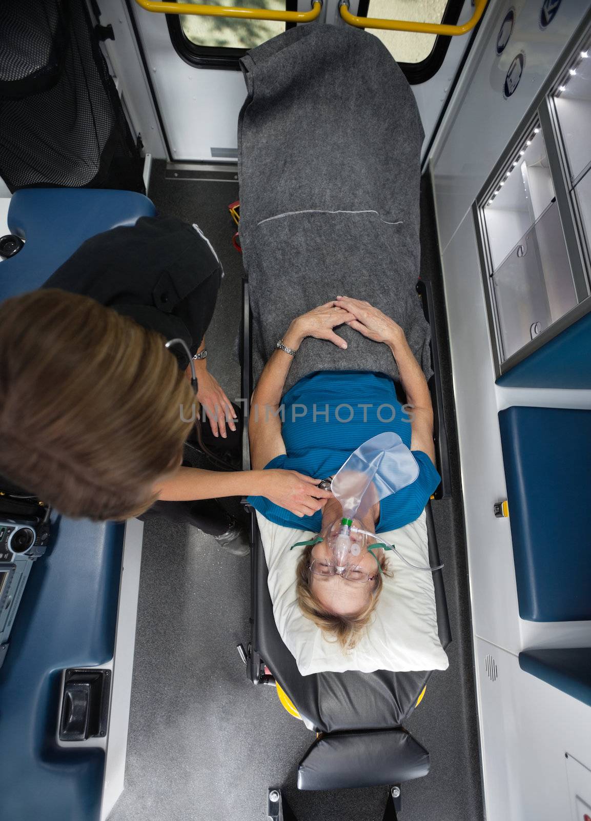 Above view of senior woman in ambulance with EMT worker