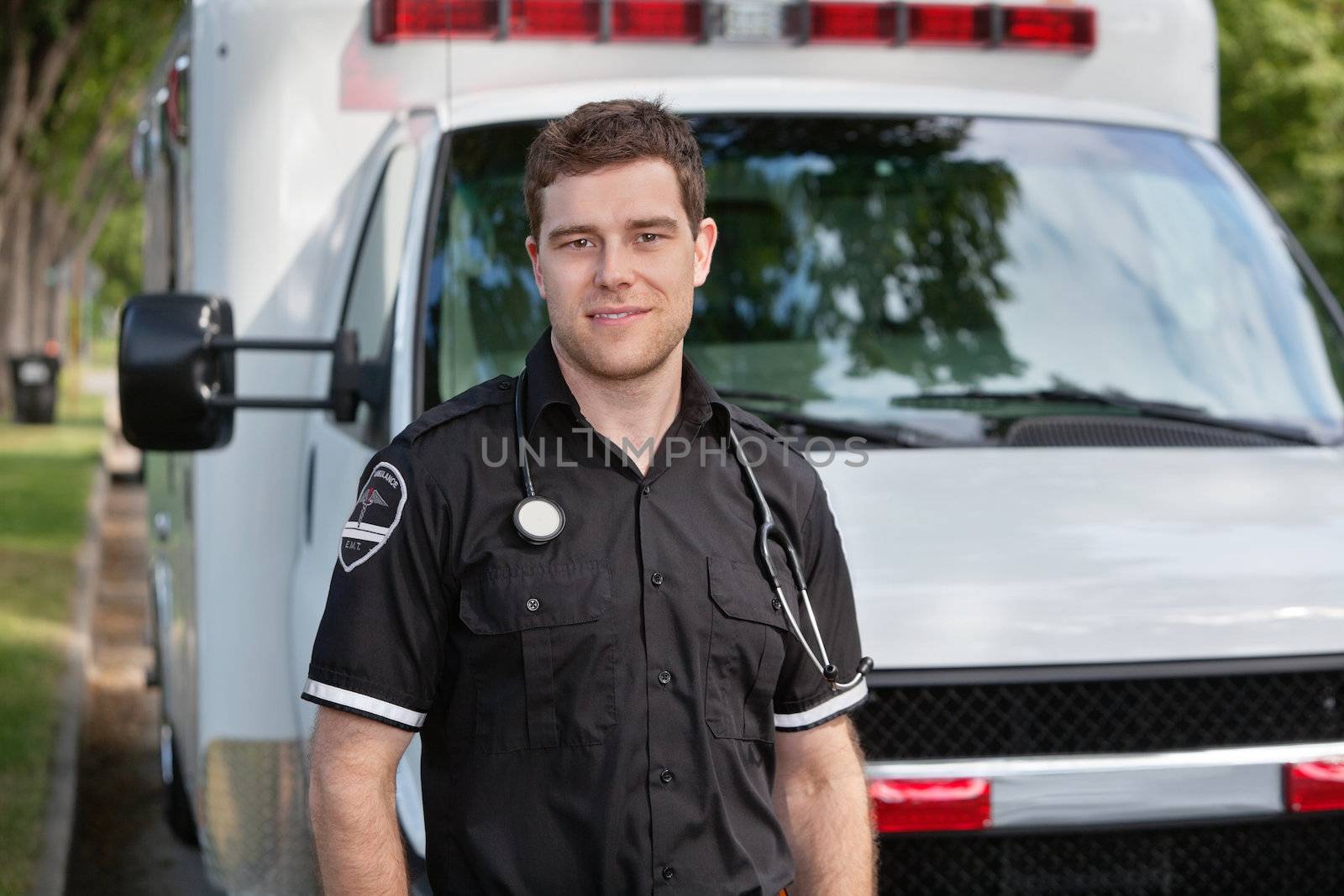 Portrait of young paramedic standing in front of white ambulance