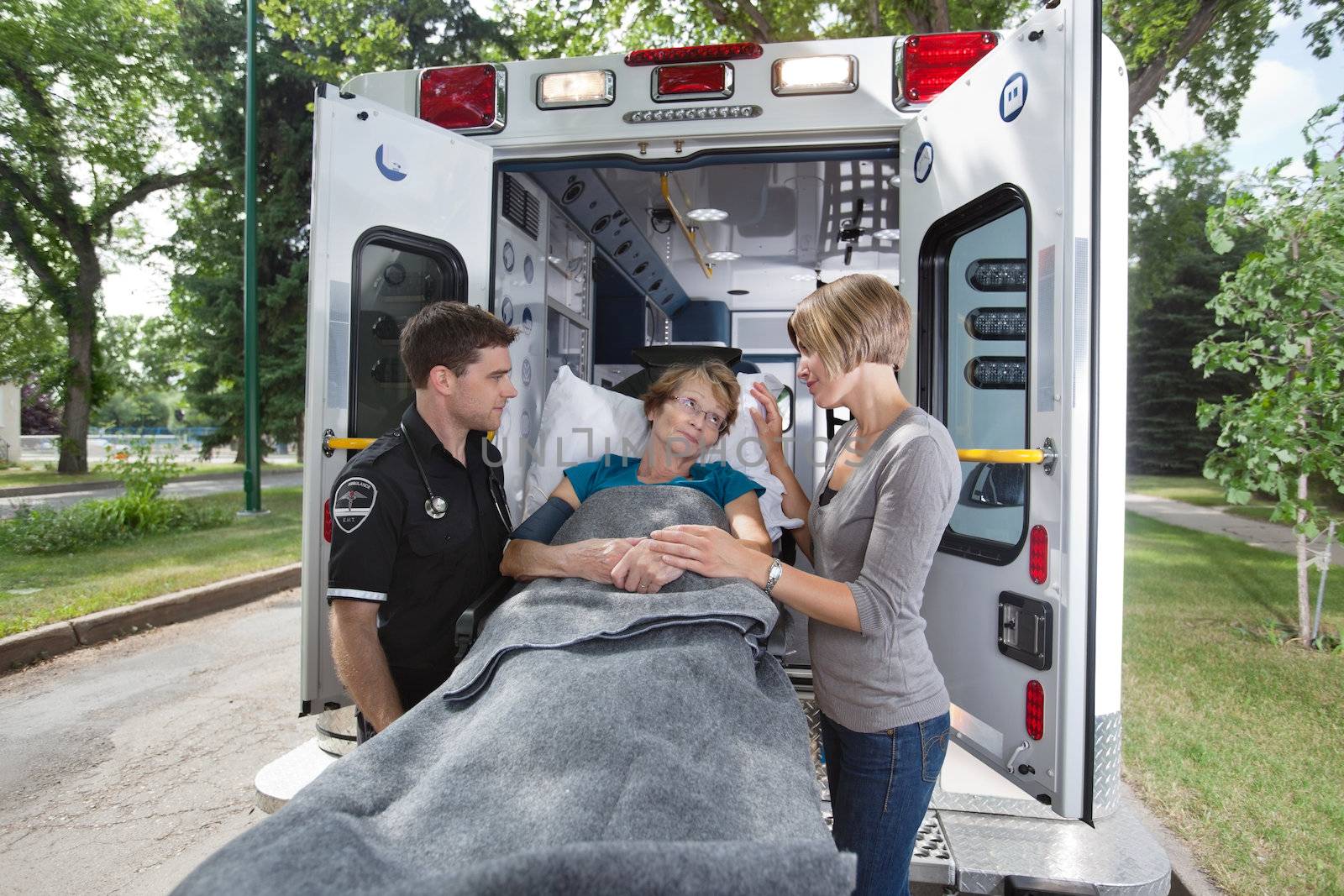 Senior woman looking at daughter / caregiver while entering ambulance