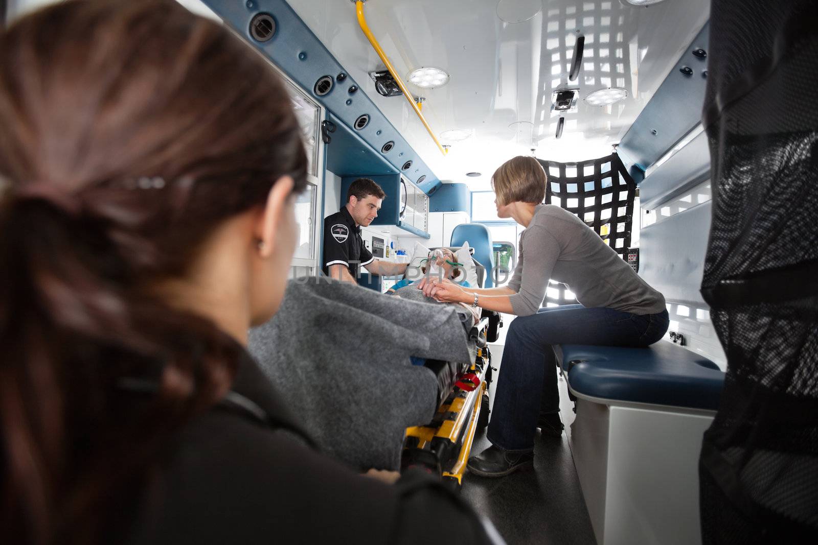 Interior of ambulance with senior woman being transported to hospital, caregiver at side