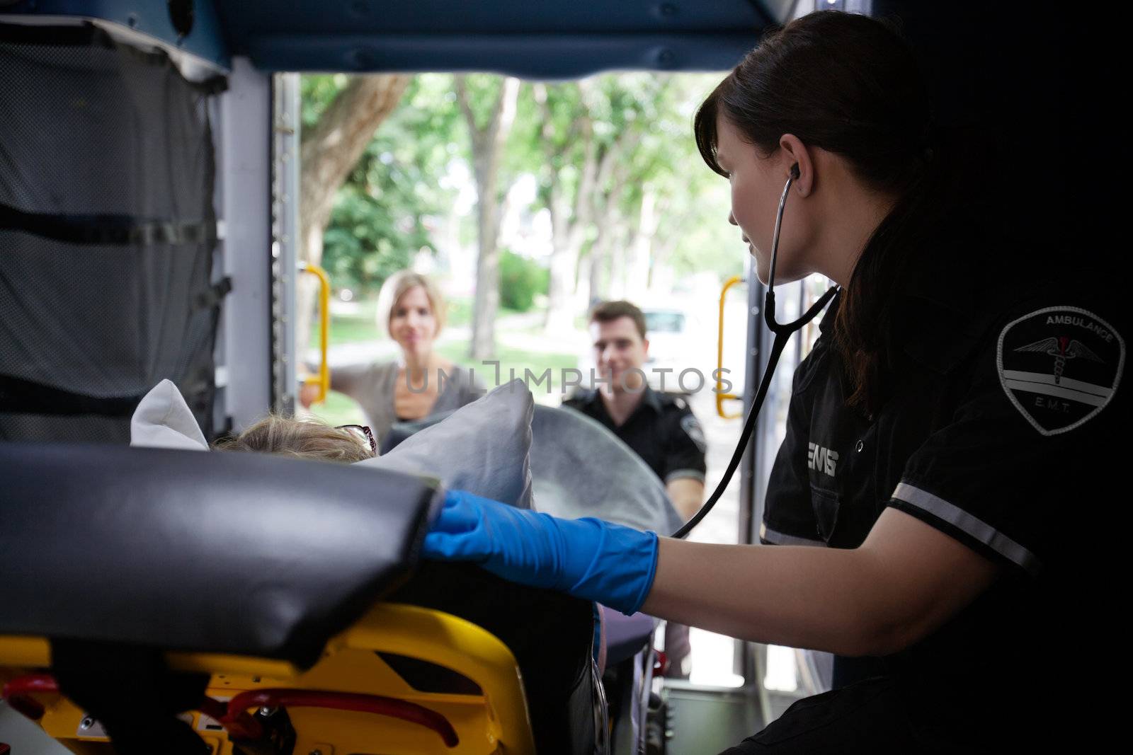 EMT worker listening to heart of elderly patient