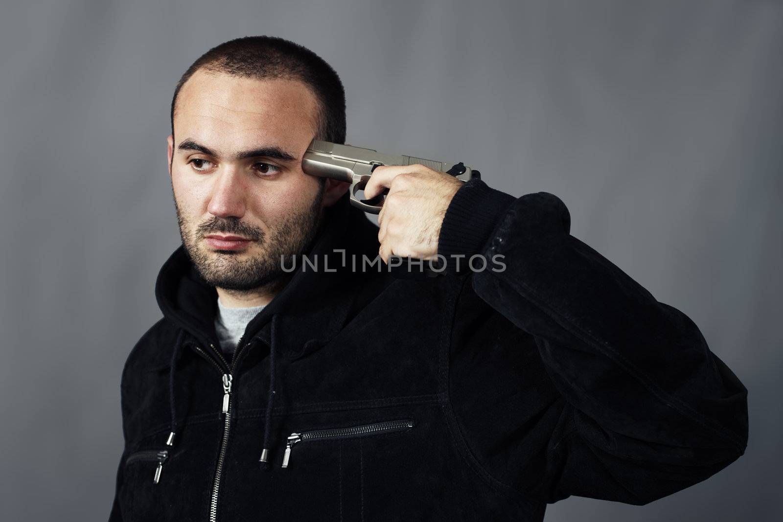 black dressed man pointing a gun at his head 