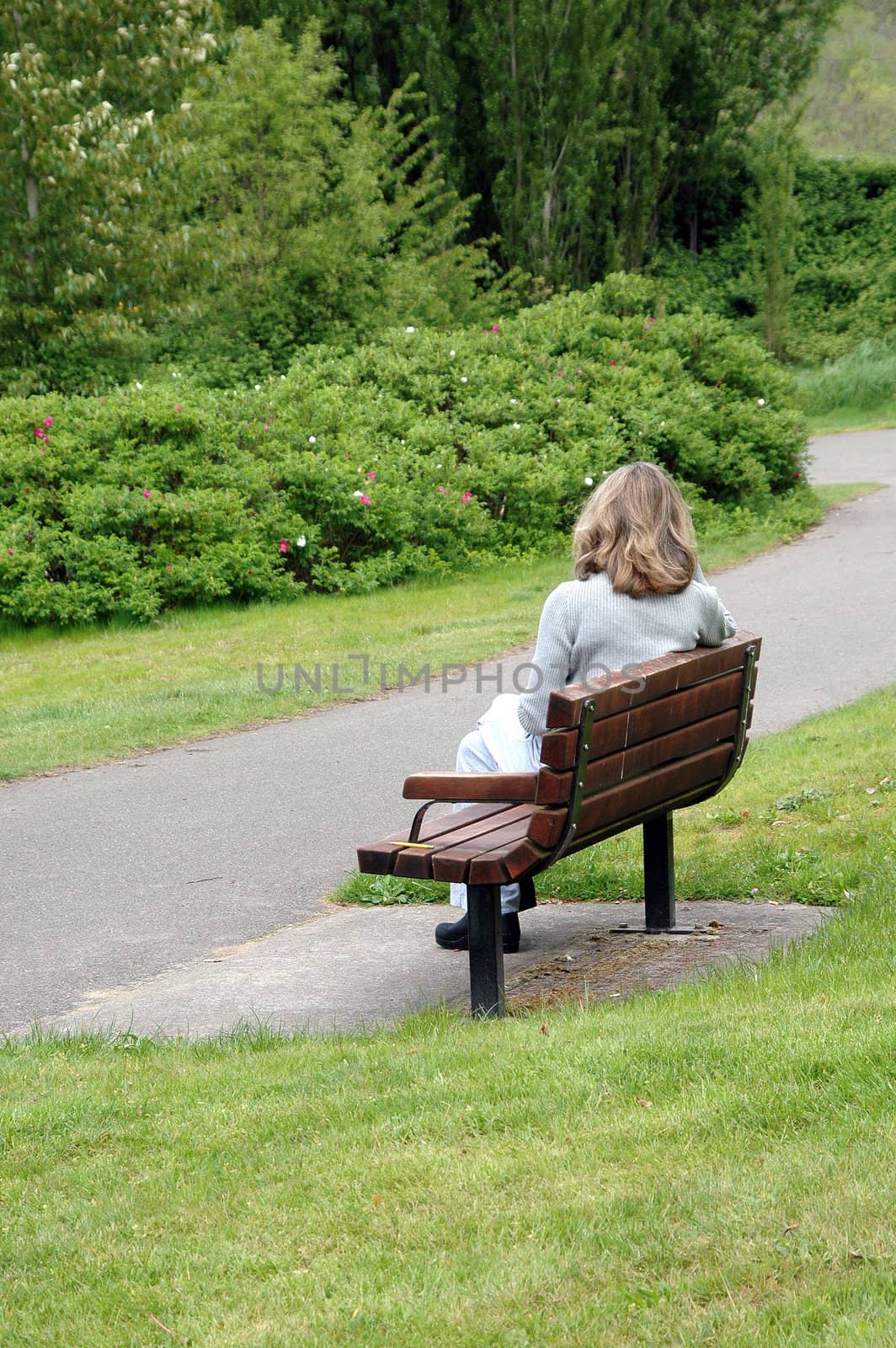 Female relaxing on park bench outside.