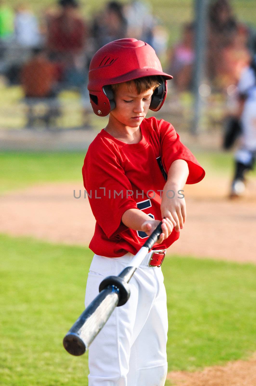Baseball boy looking down while warming up to bat.