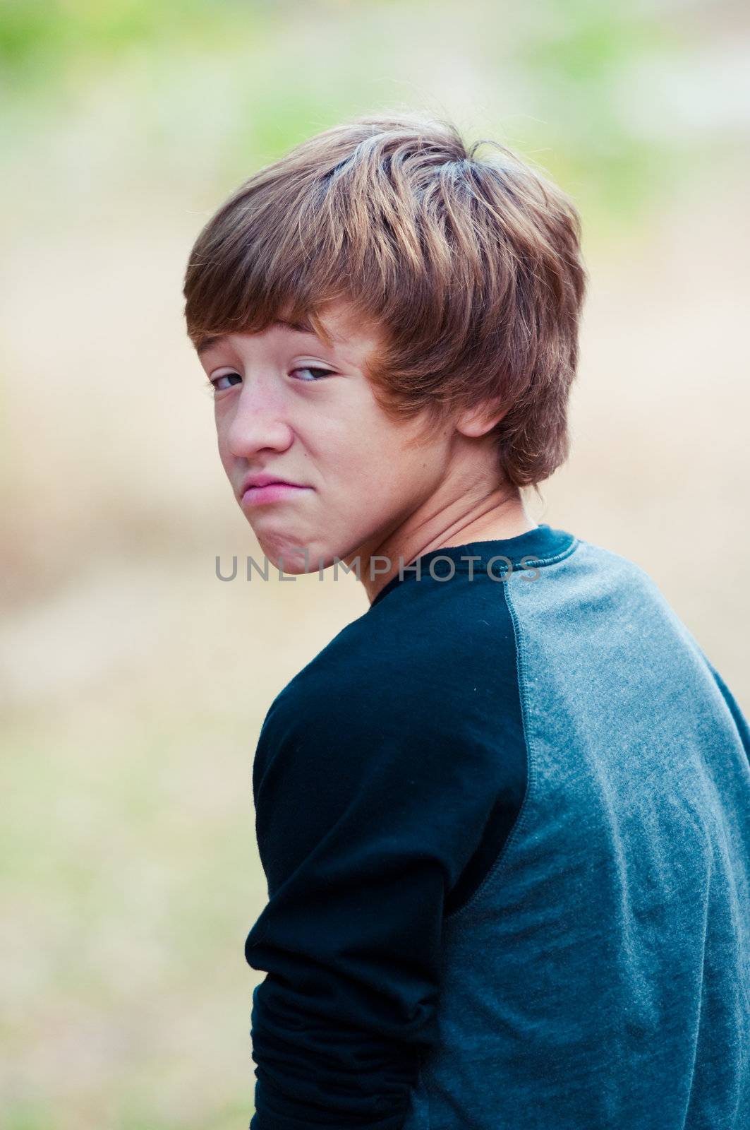 Young boy with a funny frown on his face looking at camera.