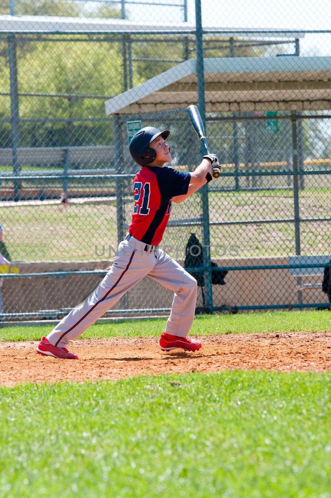 Teen boy baseball player watching ball after his hit.