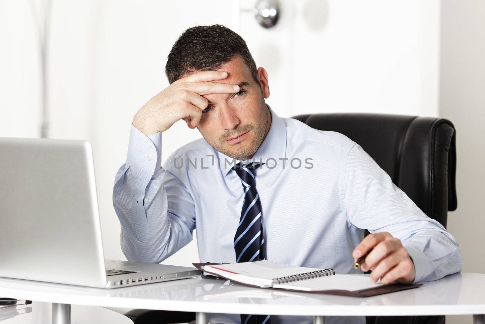 pensive man in office with computer and pen