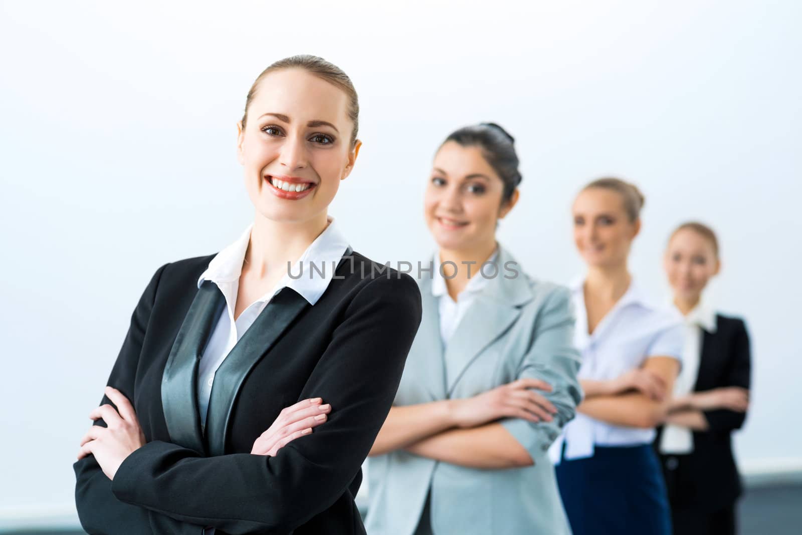 group of business people standing in a row, smiling and crossing his arms