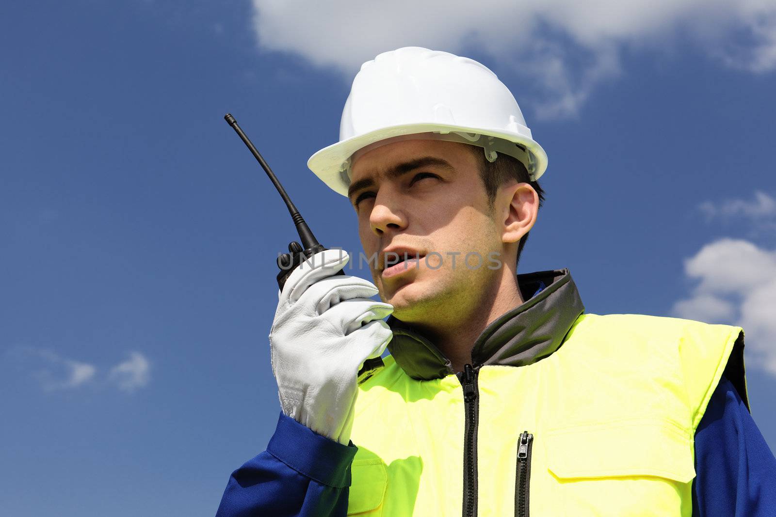portrait of builder with transmitter in blue sky