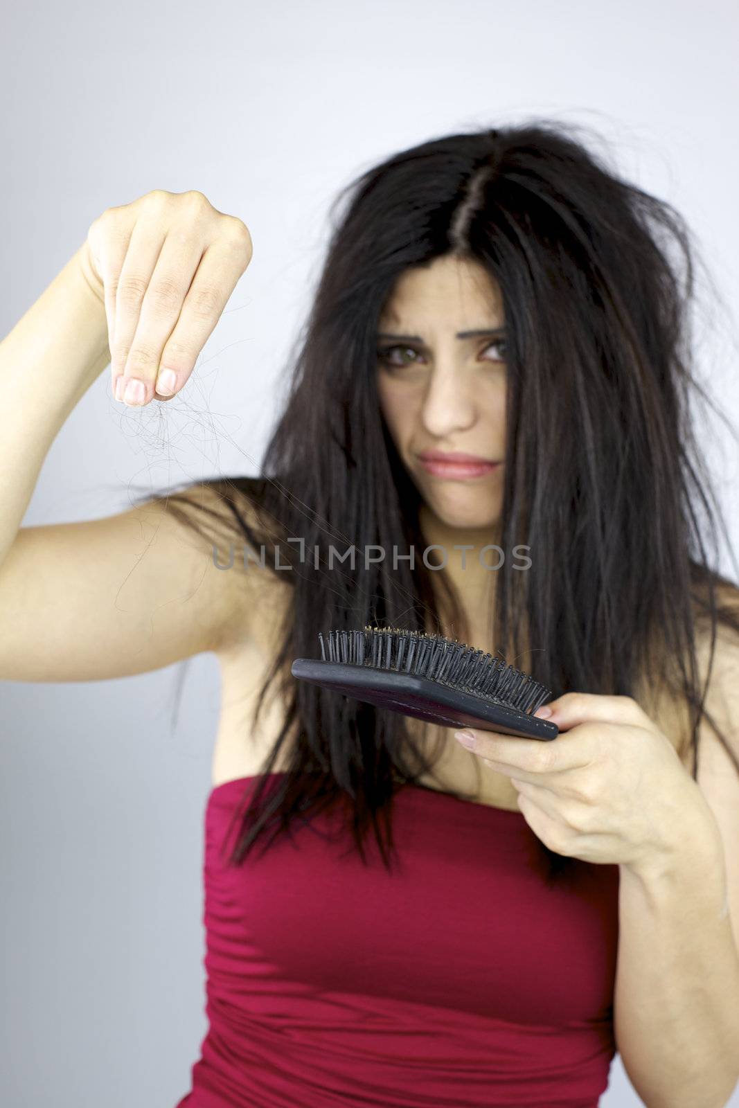 Unhappy woman holding lost hair in hand